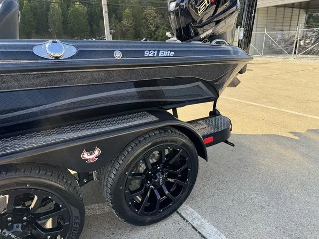 Slide: The Image of 2025 Phoenix 921 Elite boat on trailer with black wheels, parked outdoors. - 21