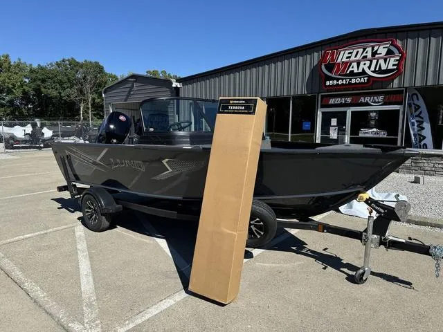 Slide: The Image of 2025 Lund 1775 Adventure Sport boat displayed outside dealership, with a tall box beside it. - 9