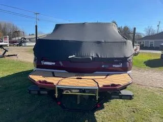 Slide: The Image of 2024 MasterCraft NXT22 boat with cover, parked on grass. - 2