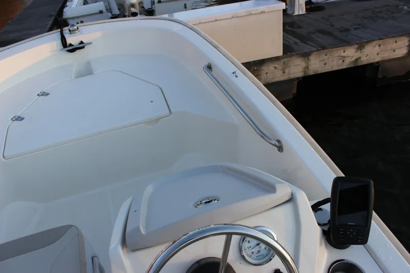 Slide: The Image of 2021 Boston Whaler 130 Super Sport boat interior with steering wheel and dock view. - 16