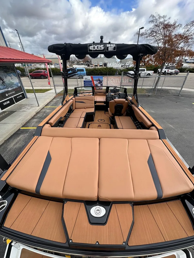 Slide: The Image of 2025 Axis Wake Research T220 boat with tan interior and black accents, parked outdoors. - 10