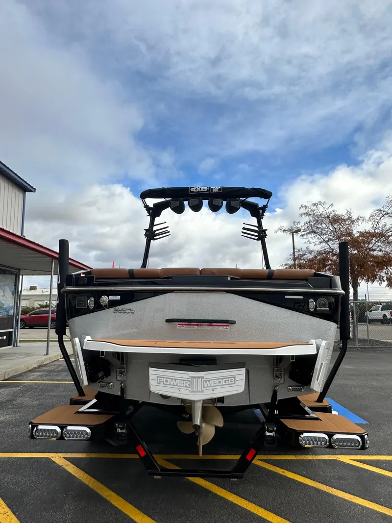 Slide: The Image of 2025 Axis Wake Research T220 boat, rear view, parked under cloudy sky. - 9