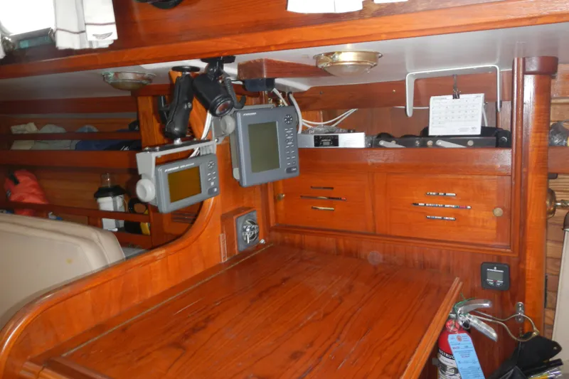 Slide: The Image of Navigation station inside a 1986 Cape Dory 36 sailboat with wooden cabinetry and electronic equipment. - 11