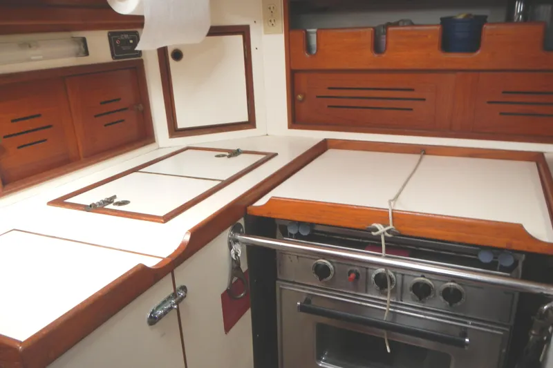 Slide: The Image of 1986 Cape Dory 36 yacht kitchen with stove, wooden cabinets, and white countertops. - 12