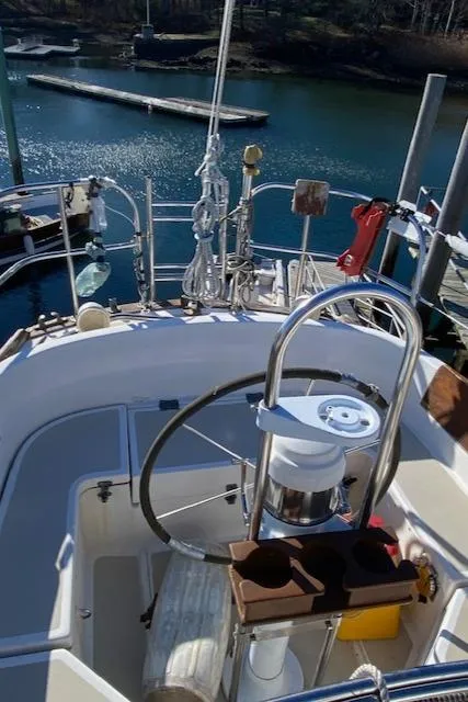 Slide: The Image of 1986 Cape Dory 36 sailboat cockpit with steering wheel, docked by calm water. - 5