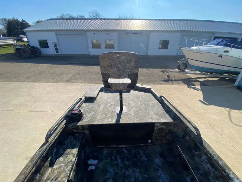 Slide: The Image of 2025 Excel 1854 F4 Shallow Water boat with camo seat, parked near showroom. - 11