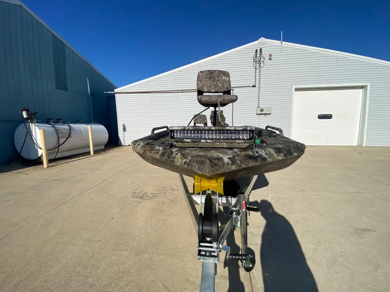 Slide: The Image of 2025 Excel 1854 F4 Shallow Water boat on trailer, parked outside industrial building. - 7