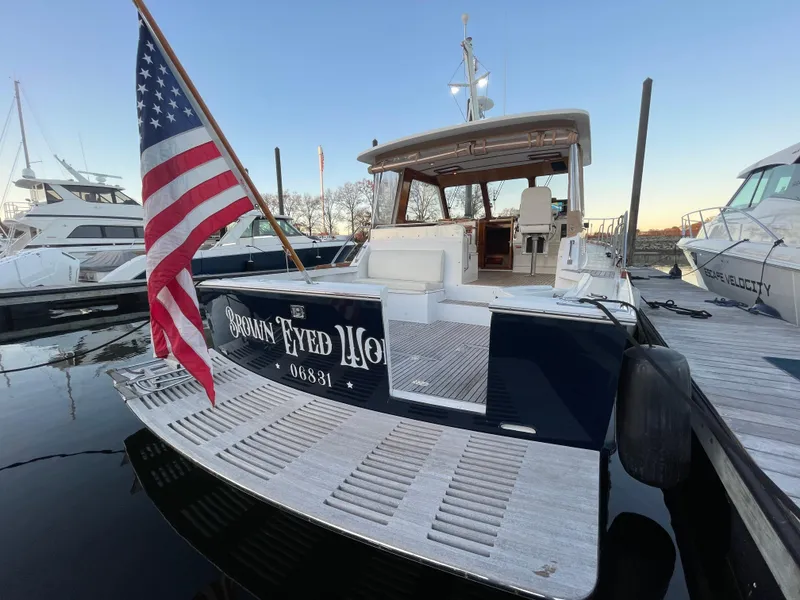 Slide: The Image of 2001 Grand Banks Eastbay 38 HX yacht docked, featuring spacious deck and American flag. - 19