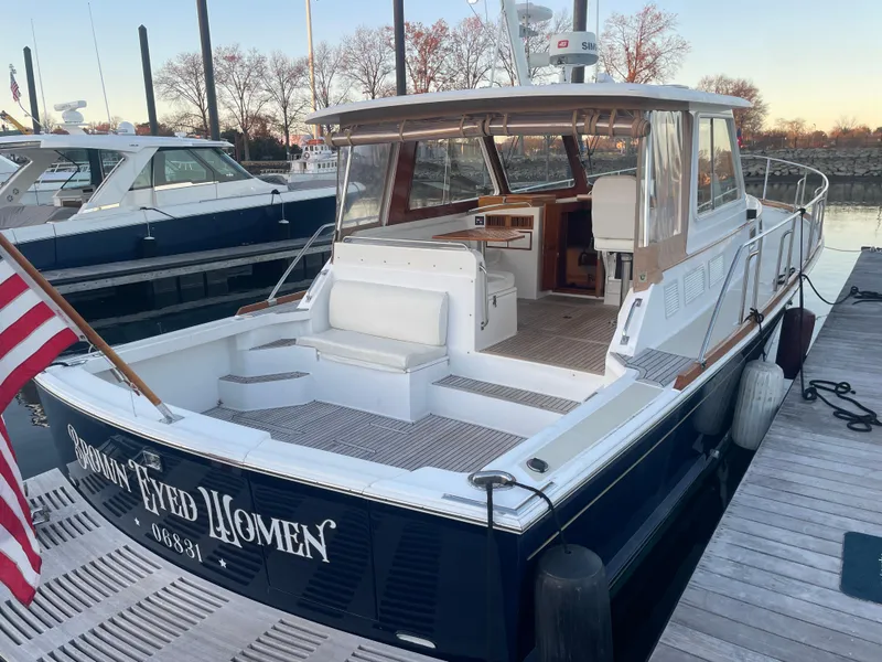 Slide: The Image of 2001 Grand Banks Eastbay 38 HX docked, featuring spacious deck and American flag. - 17