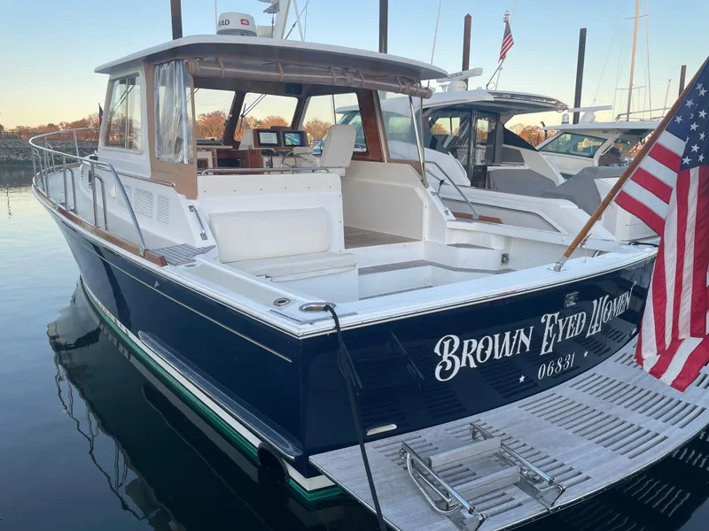 Slide: The Image of 2001 Grand Banks Eastbay 38 HX yacht docked, featuring spacious deck and American flag. - 18