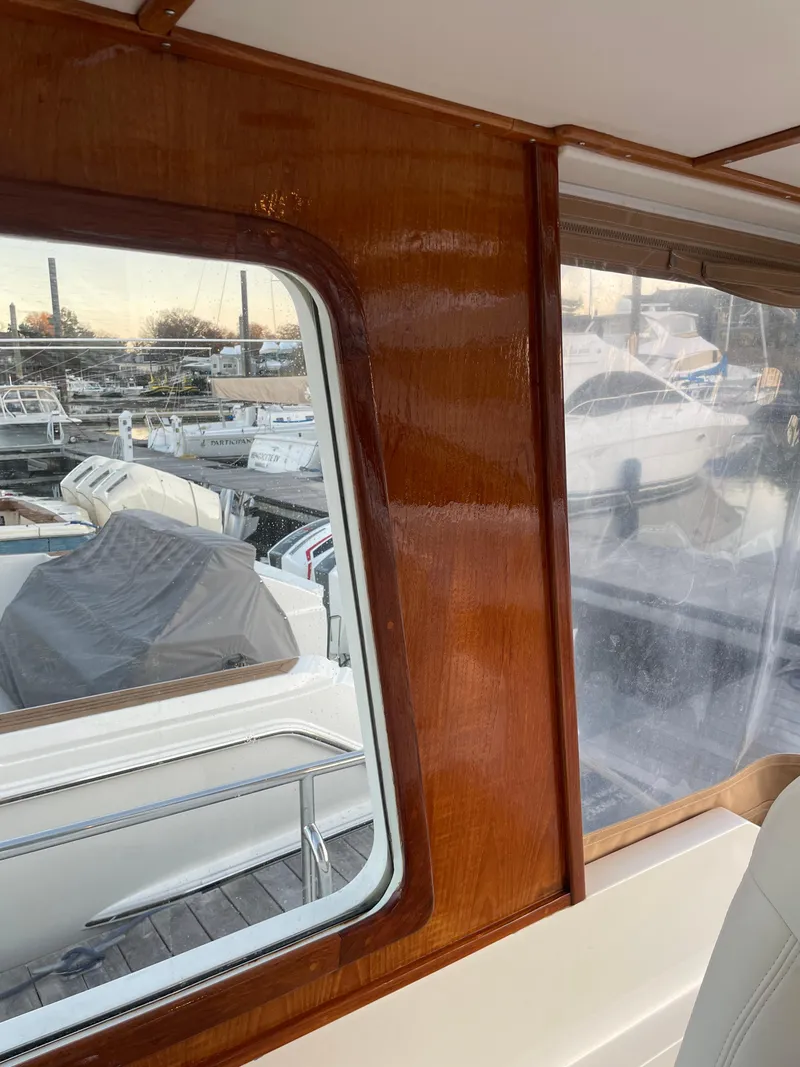 Slide: The Image of Interior view of 2001 Grand Banks Eastbay 38 HX, showcasing wooden finish and marina background. - 30