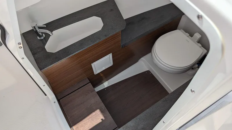 Slide: The Image of 2025 Four Winns H9 boat interior with compact bathroom, featuring a sink and toilet. - 19