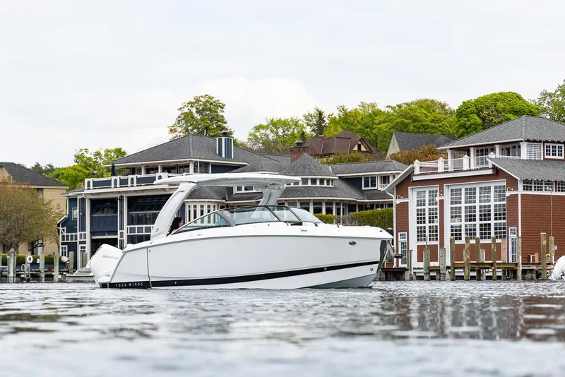 Slide: The Image of 2025 Four Winns H9 boat on a scenic waterfront with modern houses. - 28