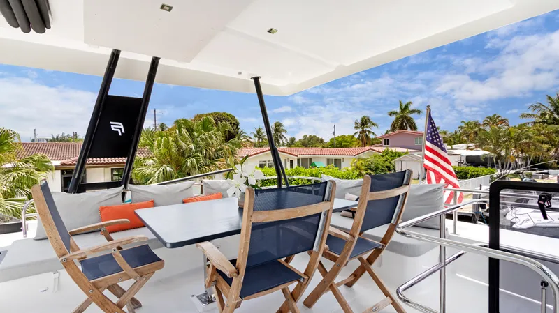 Slide: The Image of 2018 Fountaine Pajot MY 44 yacht deck with dining area, chairs, and American flag. - 43