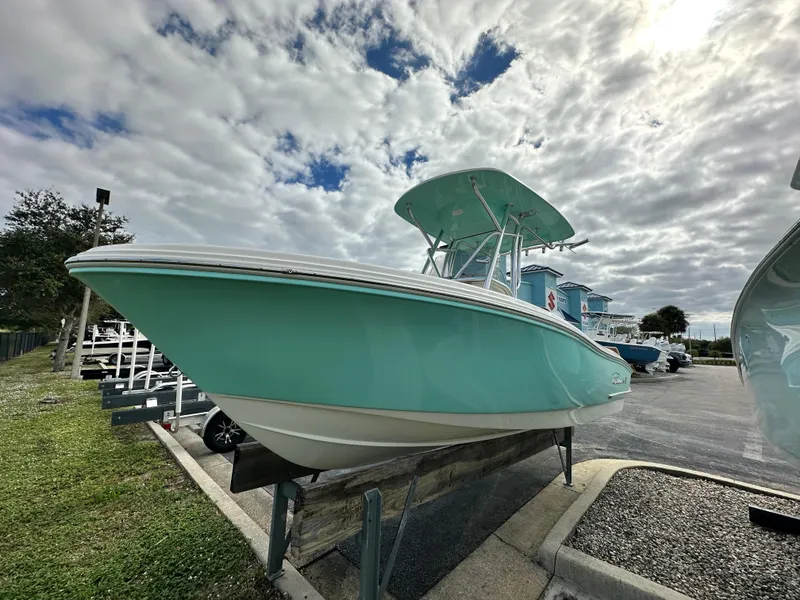 Slide: The Image of 2025 Pioneer 202 Sportfish boat in teal, displayed outdoors under a cloudy sky. - 2