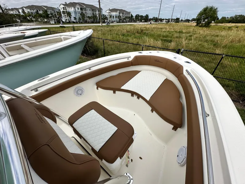 Slide: The Image of 2025 Pioneer 202 Sportfish boat interior with brown and white seating, parked outdoors. - 5