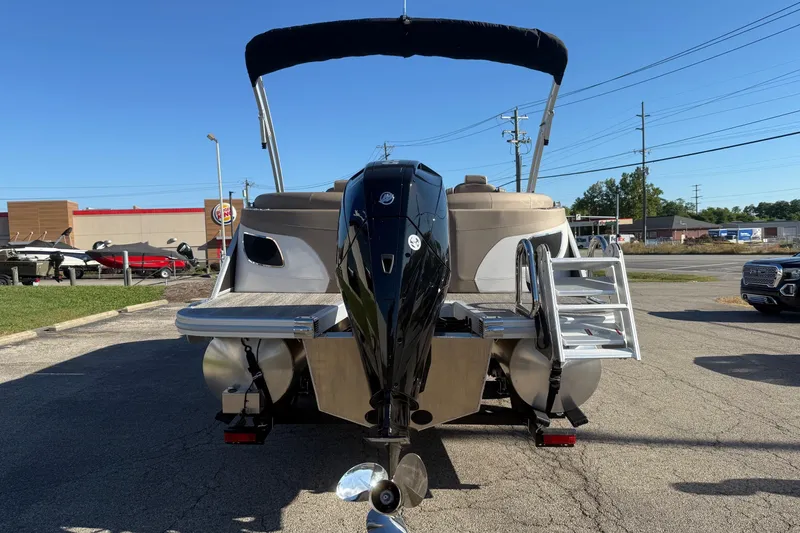 Slide: The Image of 2025 Bennington L Bowrider Line boat with outboard motor and ladder, parked outdoors. - 3
