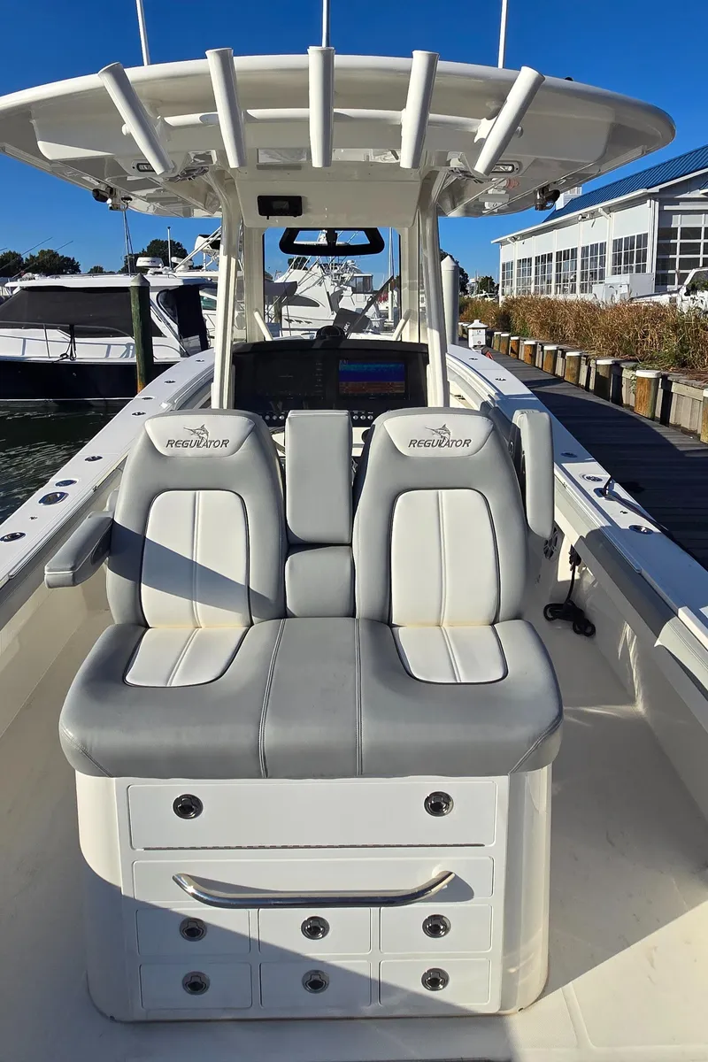 Slide: The Image of 2021 Regulator 34 Center Console boat with dual seating and storage, docked at a marina. - 14