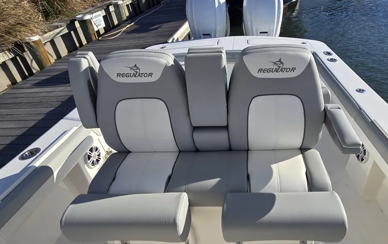 Slide: The Image of 2021 Regulator 34 Center Console boat seats with logo, docked by water. - 2