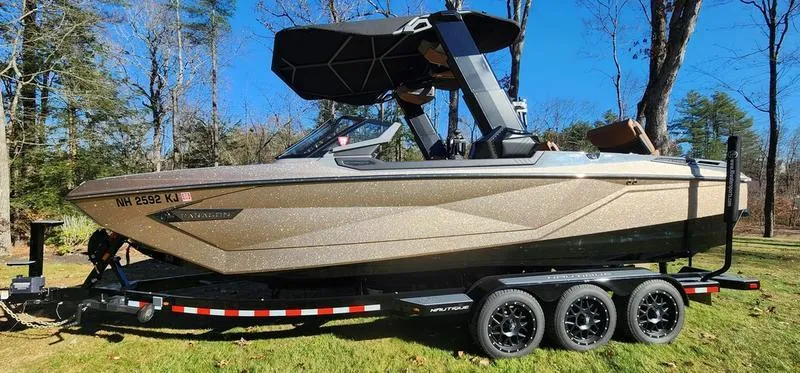 Slide: The Image of 2022 Nautique G25 Paragon boat on trailer, parked outdoors, under clear blue sky. - 3