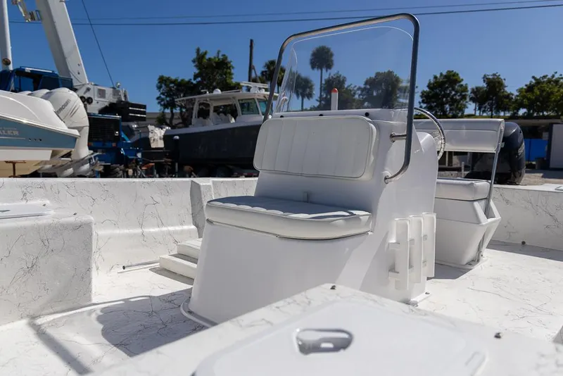 Slide: The Image of 2025 Coastal Skiff 184 boat interior with seating and console, docked under clear blue sky. - 11