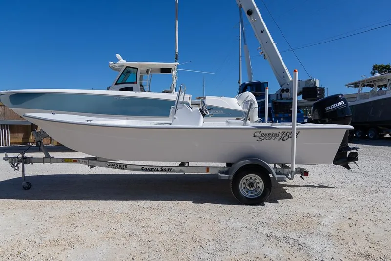 Slide: The Image of 2025 Coastal Skiff 184 boat on trailer, parked outdoors under clear blue sky. - 5