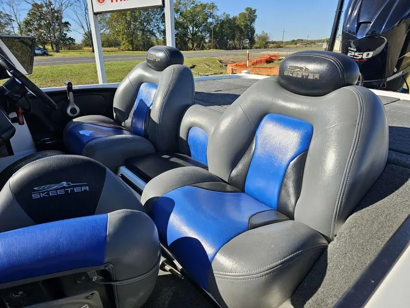 Slide: The Image of 2013 Skeeter 21i boat seats, gray and blue, with Skeeter logo, outdoors. - 6