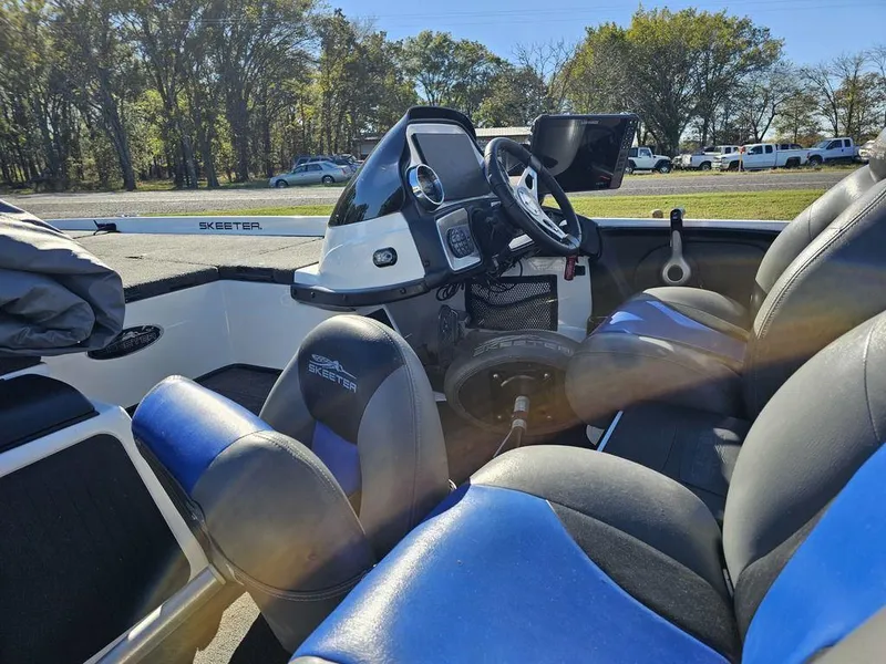 Slide: The Image of 2013 Skeeter 21i boat interior with blue and black seats, steering console, and outdoor setting. - 8