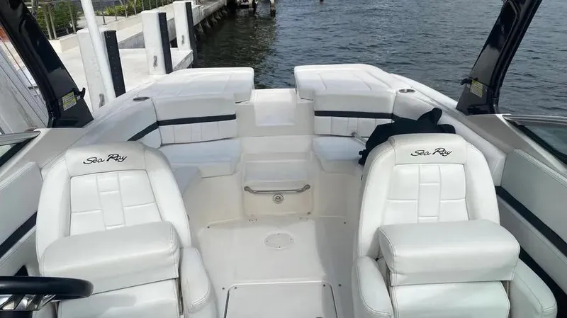 Slide: The Image of 2015 Sea Ray 250 SLX boat interior with white seating, docked by the water. - 15