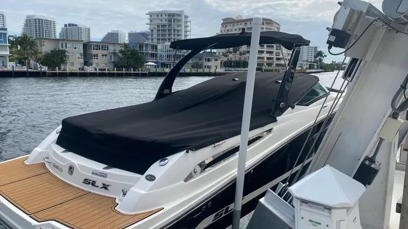 Slide: The Image of 2015 Sea Ray 250 SLX boat docked with cover, cityscape in background. - 31