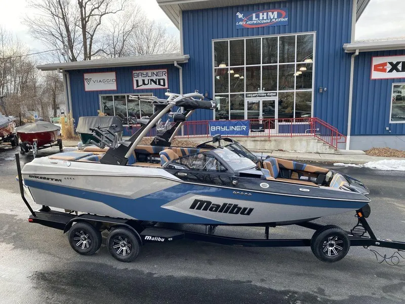The Image of 2025 Malibu 22 MXZ boat on trailer outside dealership, showcasing sleek design and modern features. - 1
