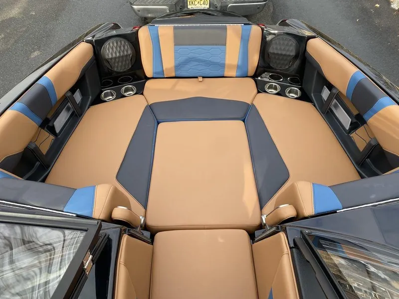 Slide: The Image of 2025 Malibu Wakesetter 22 MXZ interior with tan and blue seating, cup holders, and speakers. - 13