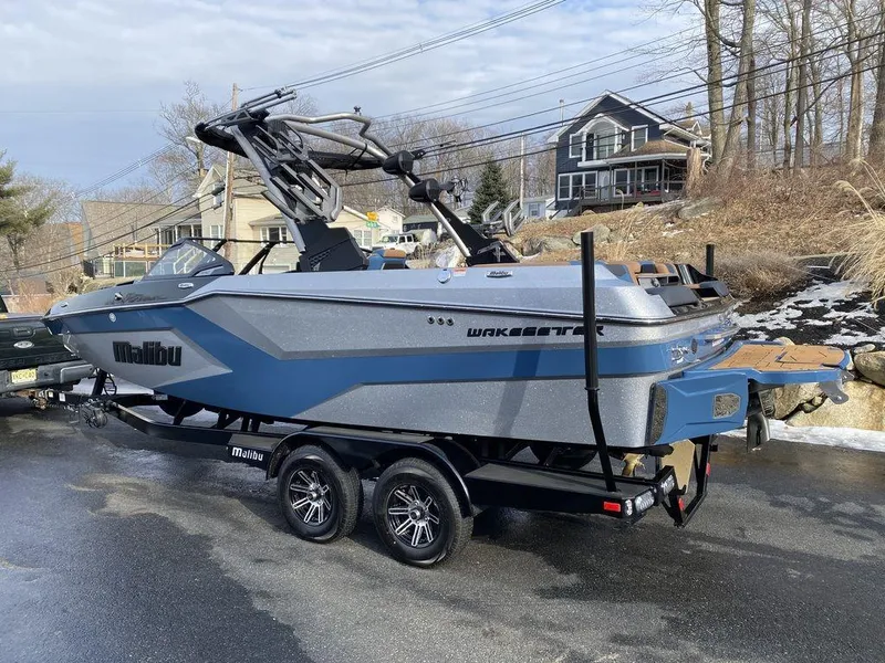 Slide: The Image of 2025 Malibu Wakesetter 22 MXZ boat on trailer, sleek design, parked outdoors. - 6