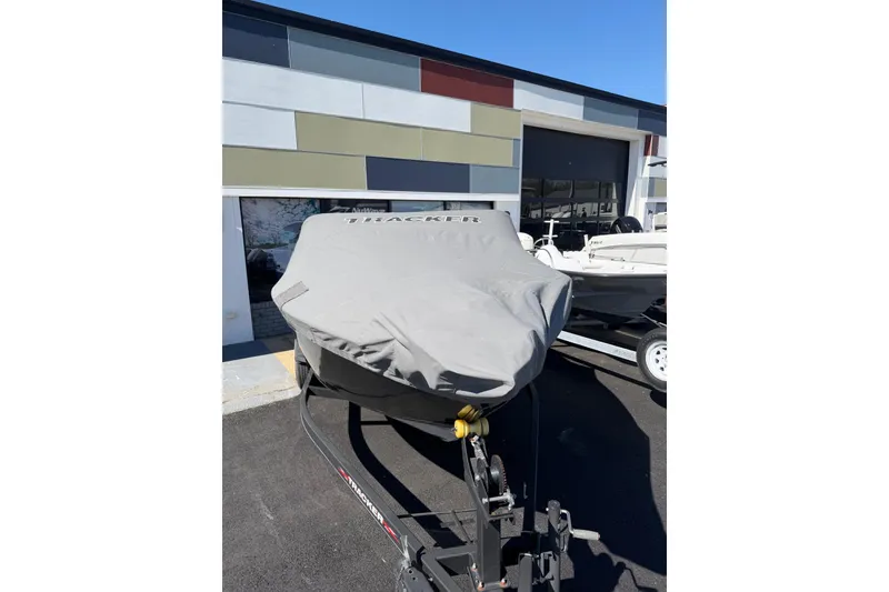Slide: The Image of 2022 Tracker Pro Guide V-175 WT boat covered, parked outside a modern building. - 17