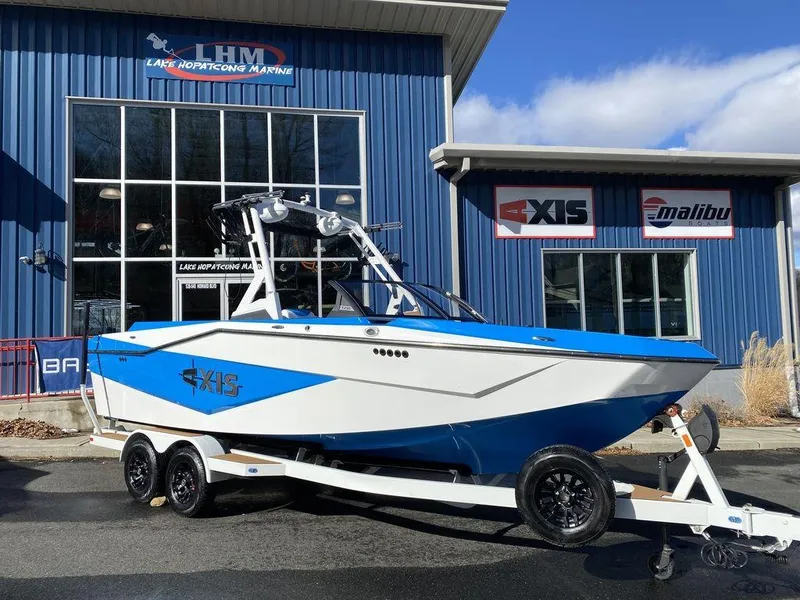 The Image of 2025 Axis T235 boat on trailer outside dealership, blue and white design. - 1