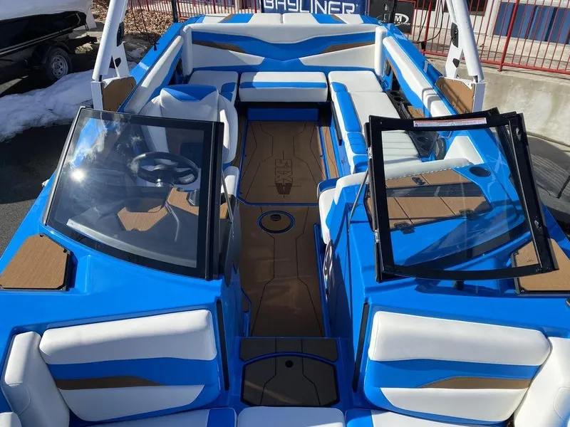 Slide: The Image of 2025 Axis T235 boat interior with blue and white seating, open windshield, and steering wheel. - 12