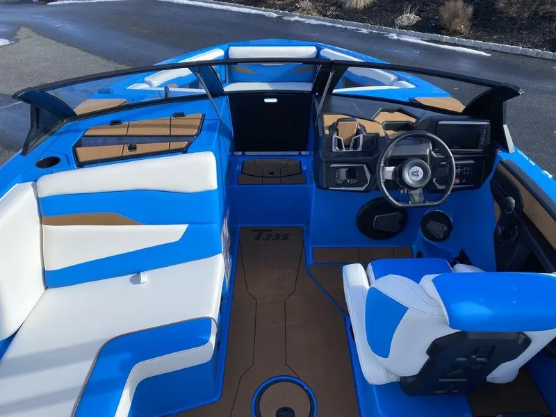 Slide: The Image of 2025 Axis T235 boat interior with blue and white seating, modern dashboard, and steering wheel. - 16
