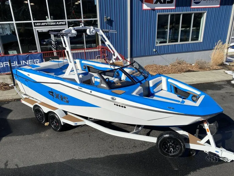 Slide: The Image of 2025 Axis T235 boat, blue and white, on a trailer outside a marine shop. - 19