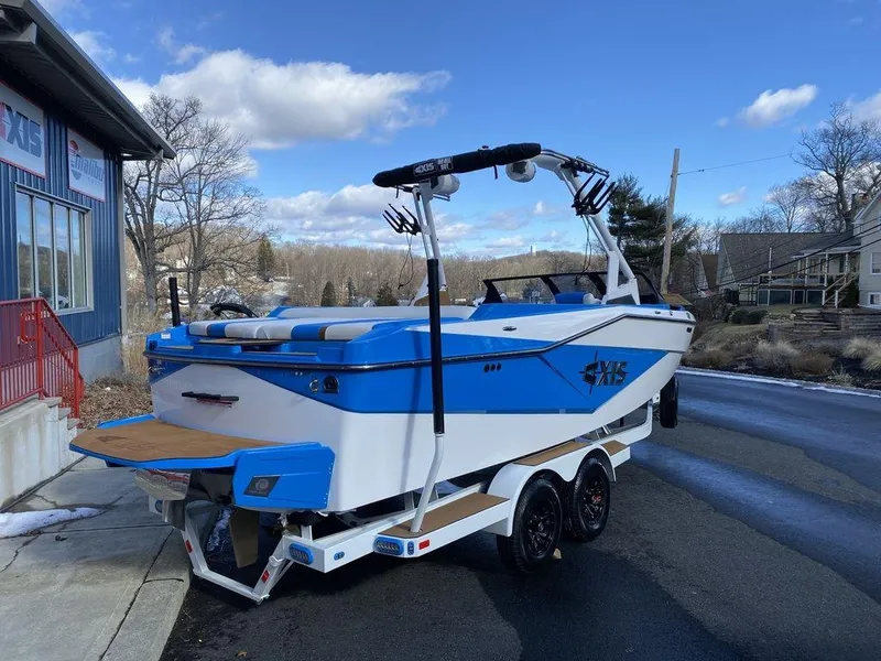 Slide: The Image of 2025 Axis T235 boat in blue and white on a trailer, parked outdoors. - 3