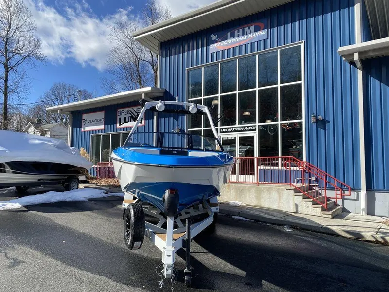 Slide: The Image of 2025 Axis T235 boat parked outside a blue building under a clear sky. - 5