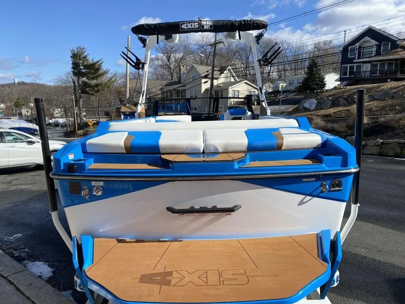Slide: The Image of 2025 Axis T235 boat with blue and white seating, parked outdoors on a sunny day. - 6
