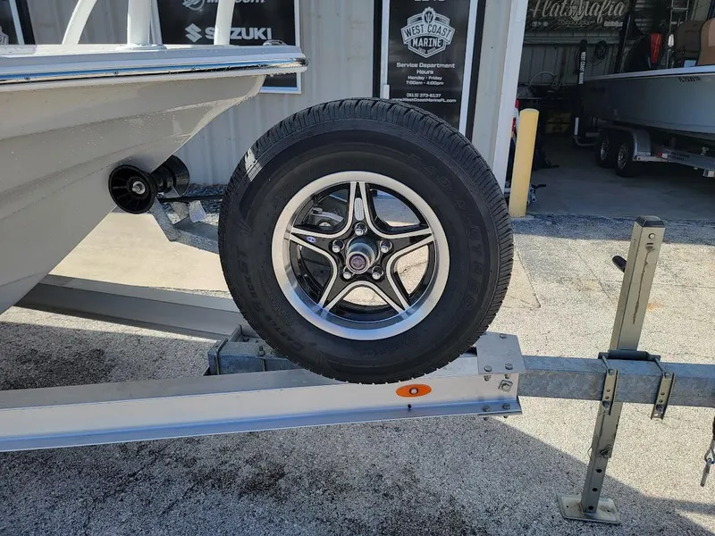 Slide: The Image of 2025 Shallow Sport 24 Modified V boat on trailer, close-up of wheel and hull. - 6