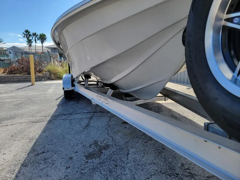 Slide: The Image of 2025 Shallow Sport 24 Modified V boat on trailer, sunny day, palm trees in background. - 7