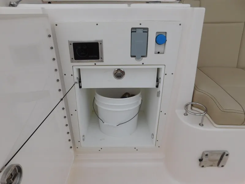 Slide: The Image of 2018 Pursuit OS 325 Offshore boat storage compartment with bucket and control panel. - 18