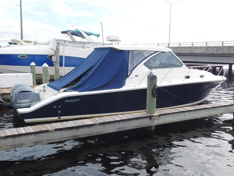 Slide: The Image of 2018 Pursuit OS 325 Offshore boat docked with blue cover, Yamaha engine visible. - 2