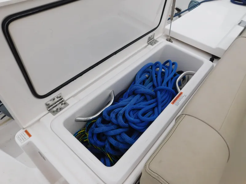 Slide: The Image of Open storage compartment on 2018 Pursuit OS 325 Offshore boat with blue ropes inside. - 25