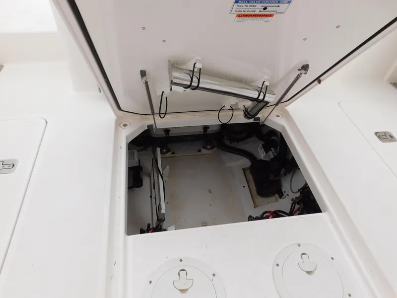 Slide: The Image of 2018 Pursuit OS 325 Offshore boat storage compartment with open hatch and visible mechanical components. - 28