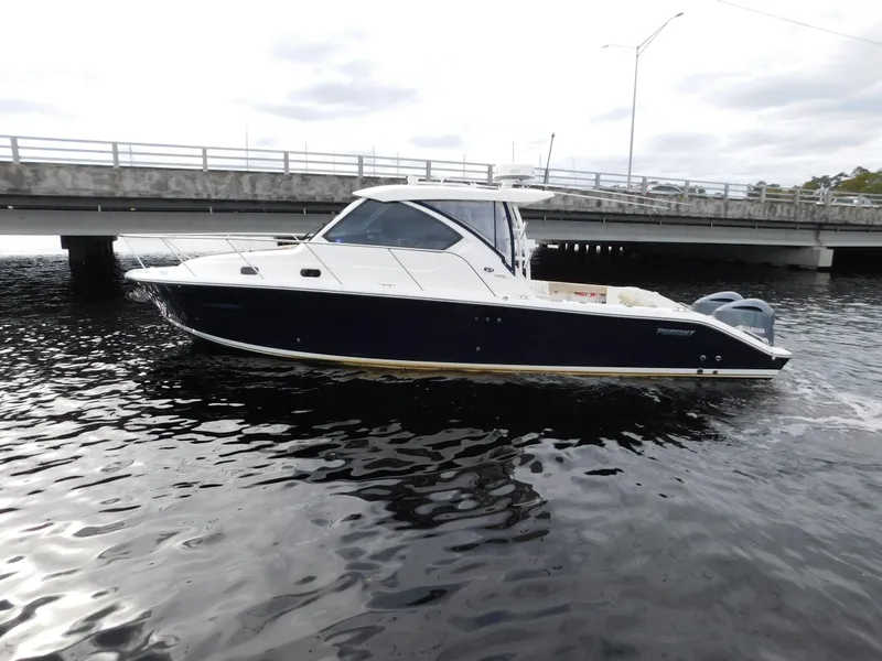 Slide: The Image of 2018 Pursuit OS 325 Offshore boat cruising near a bridge on a cloudy day. - 4