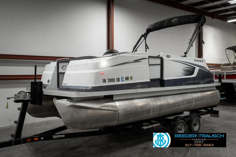 Slide: The Image of 2019 Crest Calypso 190 pontoon boat on trailer in indoor storage. - 2