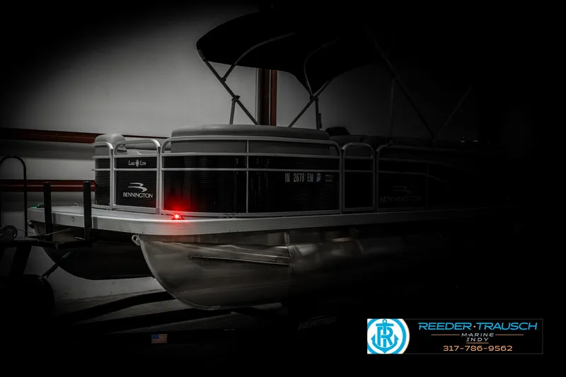 Slide: The Image of 2023 Bennington 20 SVL pontoon boat in a dimly lit showroom. - 4